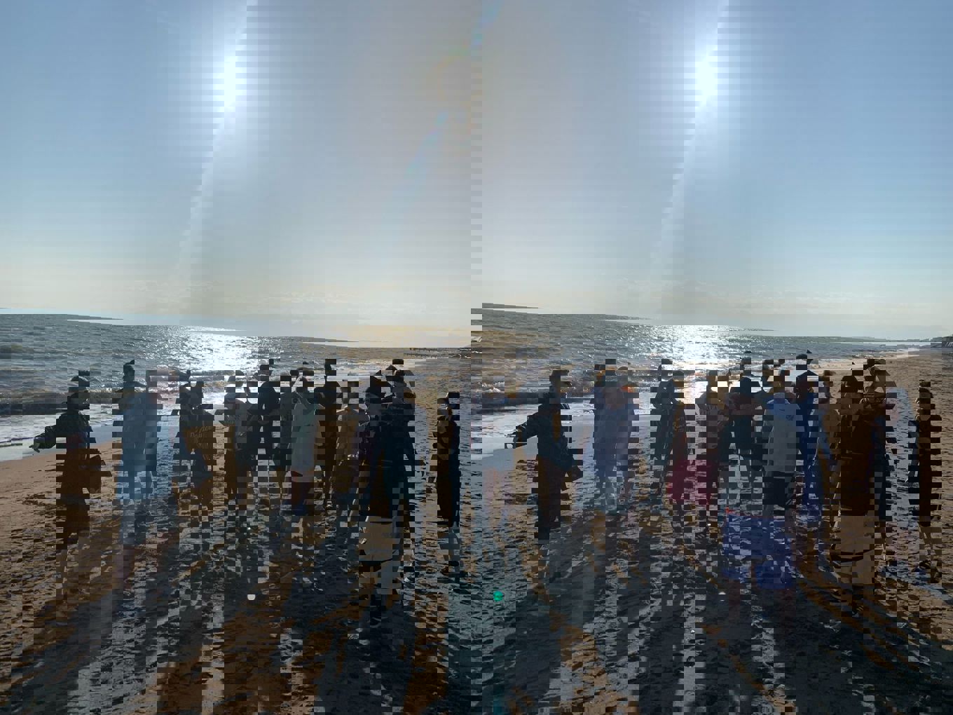 en gruppe mennesker som står på en strand en gruppe mennesker som står på en strand